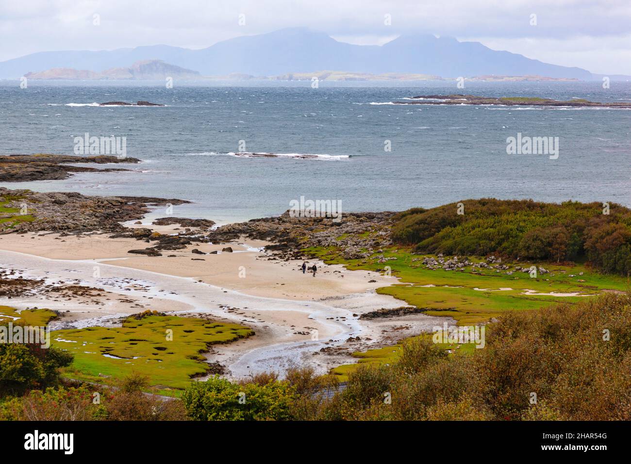 Strandspaziergänger mit weißem Sand in Portuairk, der westlichsten Siedlung auf dem britischen Festland in Westschottland mit Blick auf die kleinen Inseln Stockfoto