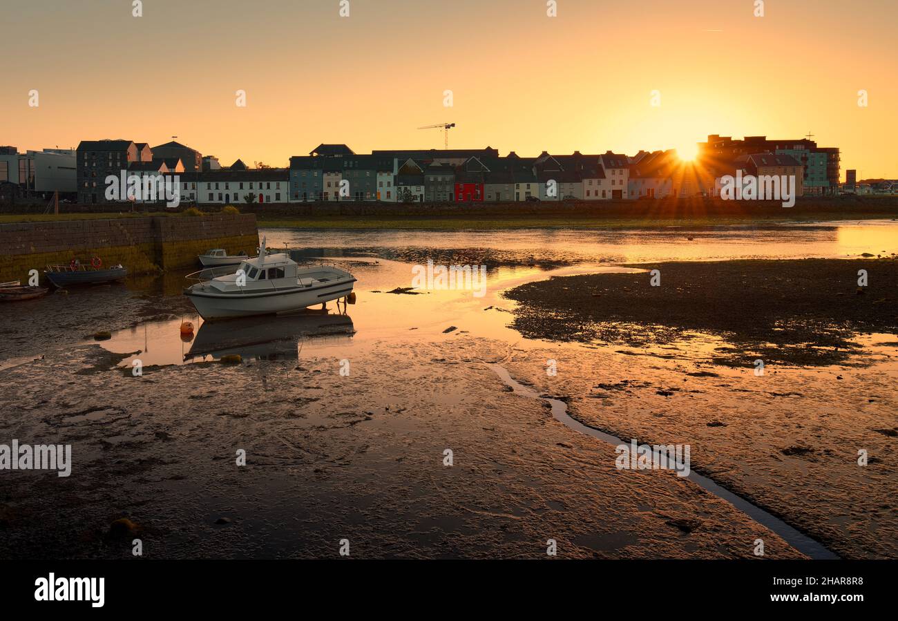 Wunderschöne Landschaft mit orangefarbenem Sonnenaufgang am Morgen mit bunten Häusern und Booten, die sich im Corrib River bei Claddagh in Galway City, Irland, widerspiegeln Stockfoto