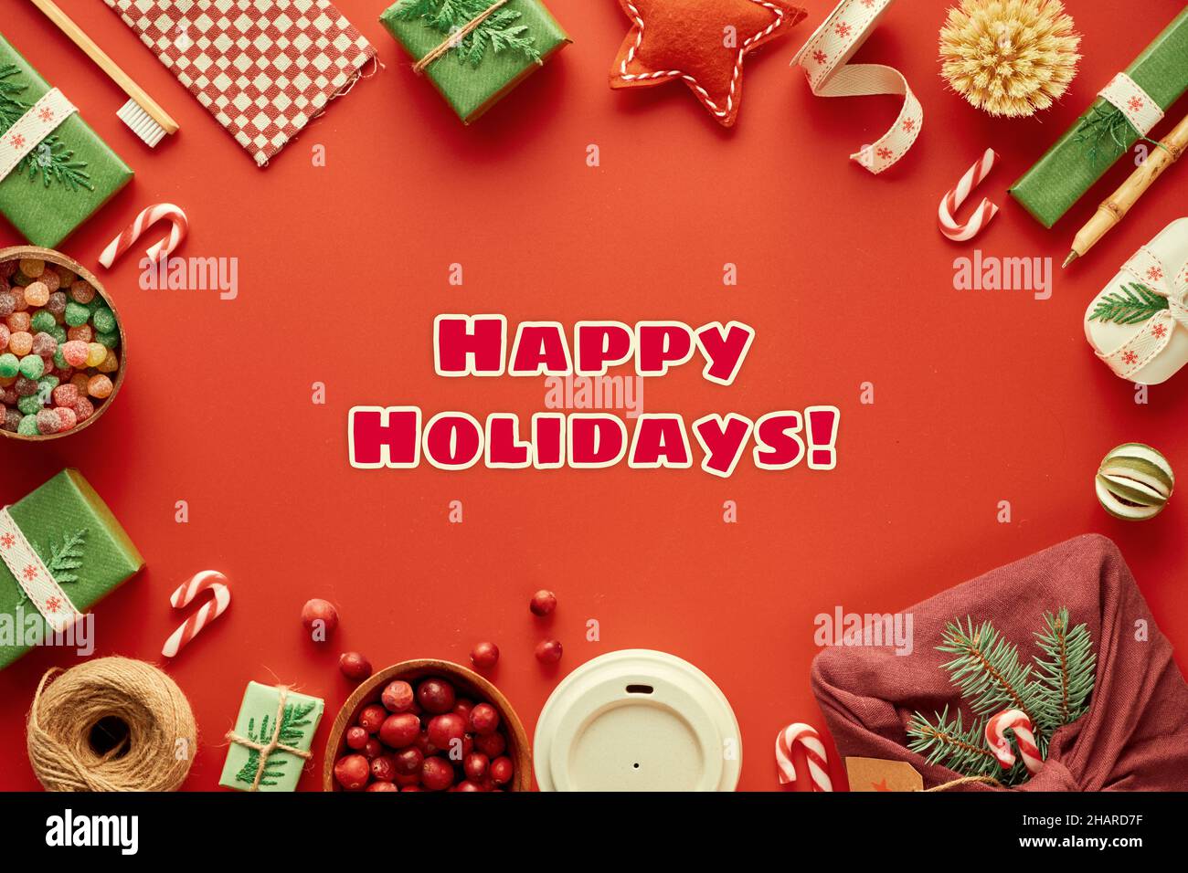 Text „Happy Holidays“. Roter, grüner und weißer Weihnachtshintergrund. Trendige umweltfreundliche Weihnachten. Neujahrsdekor, Geschenke. Geometrische flach legen mit Geschenken Stockfoto