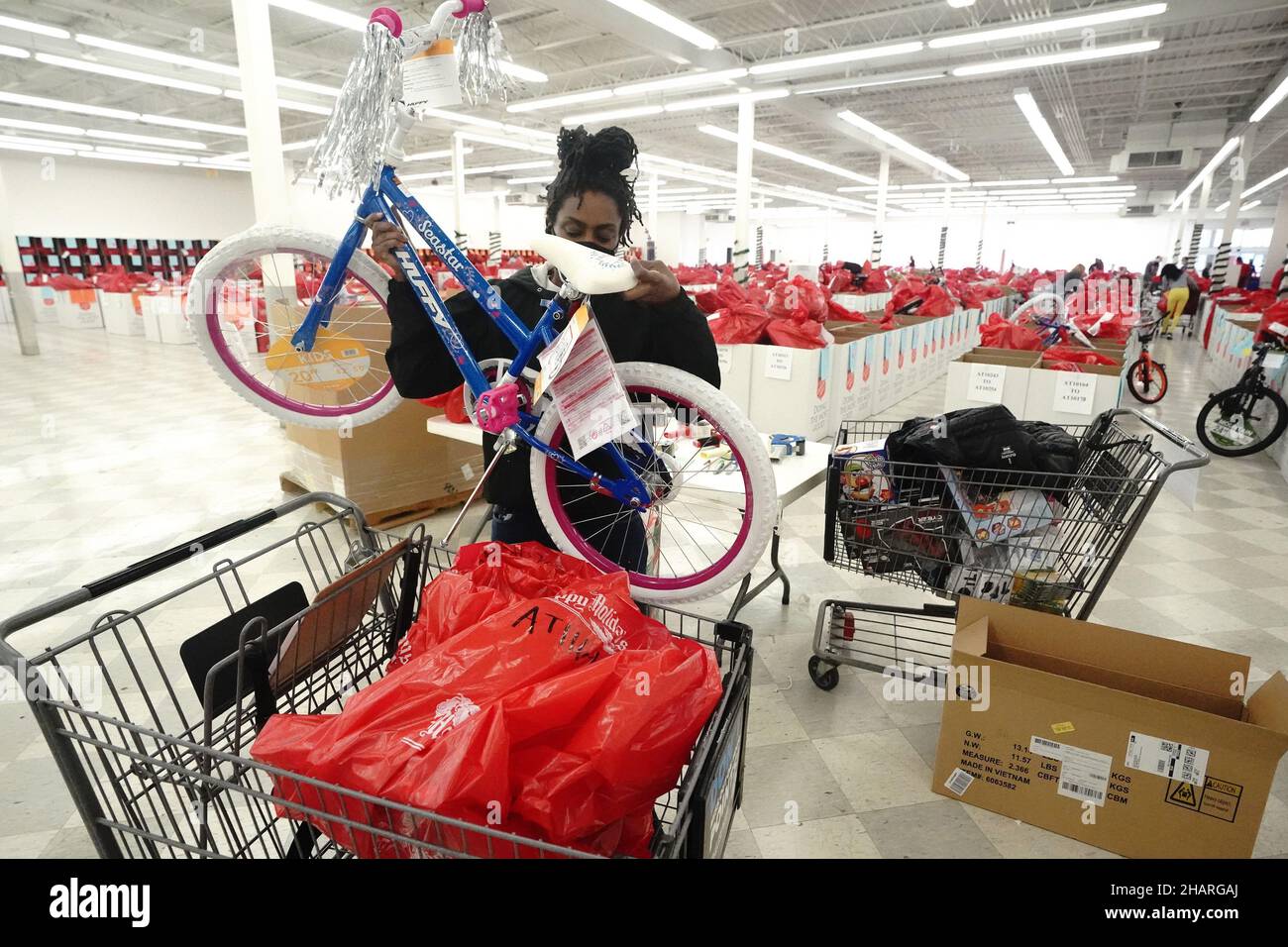 Florissant, Usa. 14th Dez 2021. Die Freiwillige Ralissa Lakine lädt am Dienstag, den 14. Dezember 2021, ein Fahrrad in einen Wagen, während sie im „Heilsarmee Angle Tree Toy Give-a-Way“ in Florissant, Missouri, für eine Familie einkaufen. Die Heilsarmee wird über 4000 Spielzeuge in drei Tagen an bedürftige Familien zu Weihnachten verschenken. Foto von Bill Greenblatt/UPI Credit: UPI/Alamy Live News Stockfoto