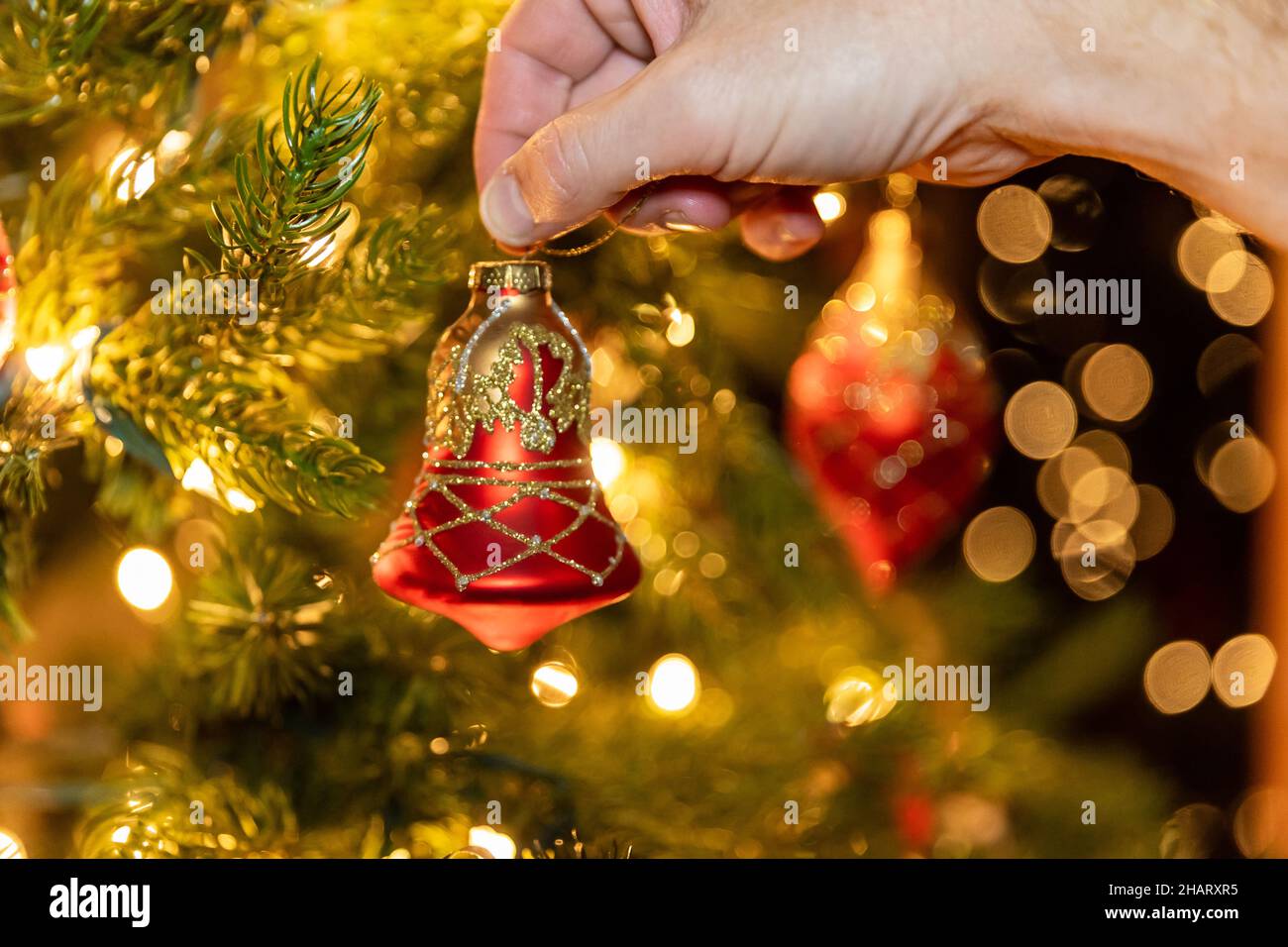 Hand hängende Weihnachtsschmuck auf Baum, mit flachem Fokus und Bokeh. Stockfoto