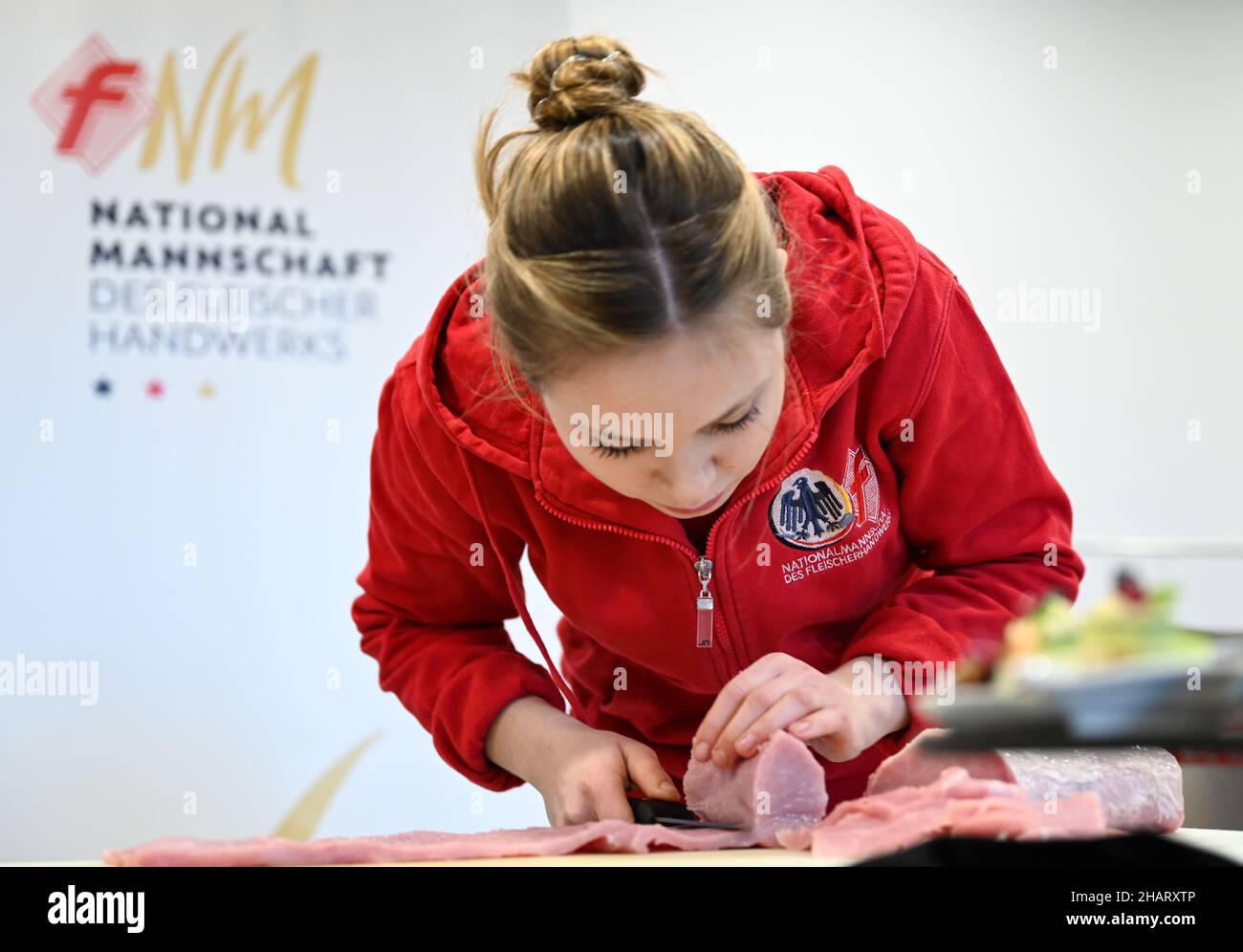 Weiterstadt, Deutschland. 22nd. November 2021. Leonie Baumeister, Vertriebsleiterin aus Waibstadt (Baden-Württemberg) und Mitglied der deutschen Metzgerei-Nationalmannschaft, schneidet Schweinefleisch für einen gerollten Braten. Die Metzgermeister, Vertriebsleiter und Sommeliers bilden ihre Fähigkeiten im einzigen bundesweiten Ausbildungszentrum in Weiterstadt in Südhessen aus. Die Metzgermeister werden von einem Mangel an jungen Talenten geplagt. Ein Nationalteam wirbt mit Imagekampagnen und konkurriert auch mit Kollegen aus anderen Ländern. Kredit: Arne Dedert/dpa/Alamy Live Nachrichten Stockfoto