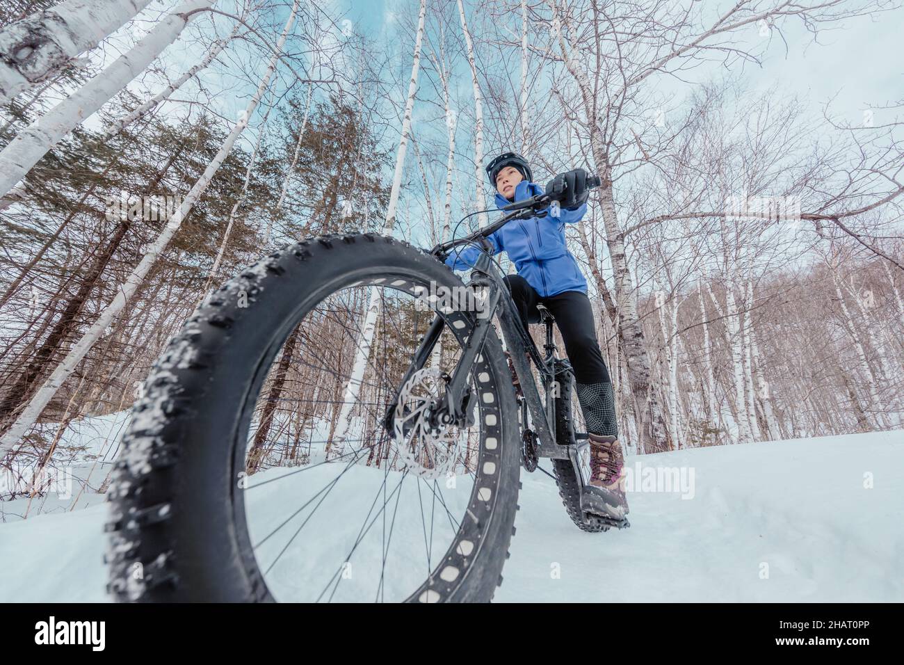 Fat Bike im Winter. Fetter Biker, der im Winter im Schnee Fahrrad fährt. Nahaufnahme von fetten Reifen-Radrädern im Schnee. Frau lebt gesund Stockfoto