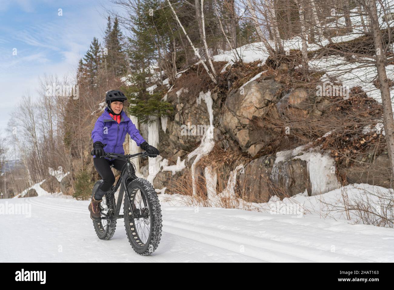 Fatbike im Winter. Frau Fat Biker Reiten Fett Fahrrad im Schnee in Winterwald Berglandschaft. Frau lebt gesund im Freien aktiv Stockfoto
