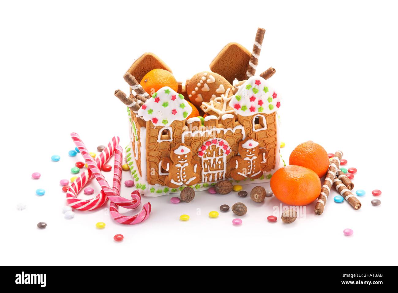 Schönes Lebkuchenhaus, Mandarinen und Leckereien isoliert auf weißem Hintergrund Stockfoto