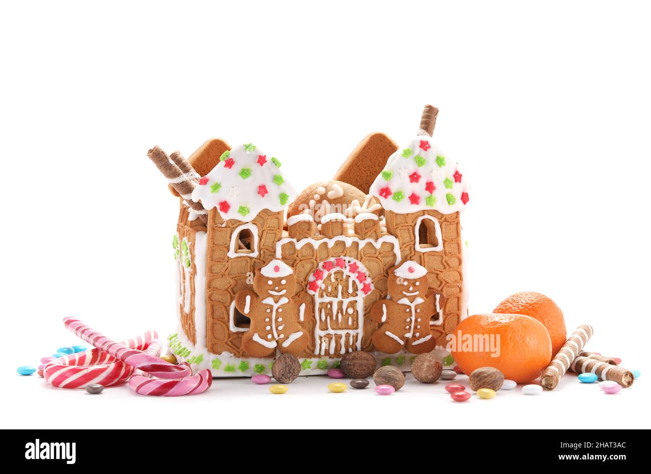 Schönes Lebkuchenhaus, Mandarinen und Leckereien isoliert auf weißem Hintergrund Stockfoto