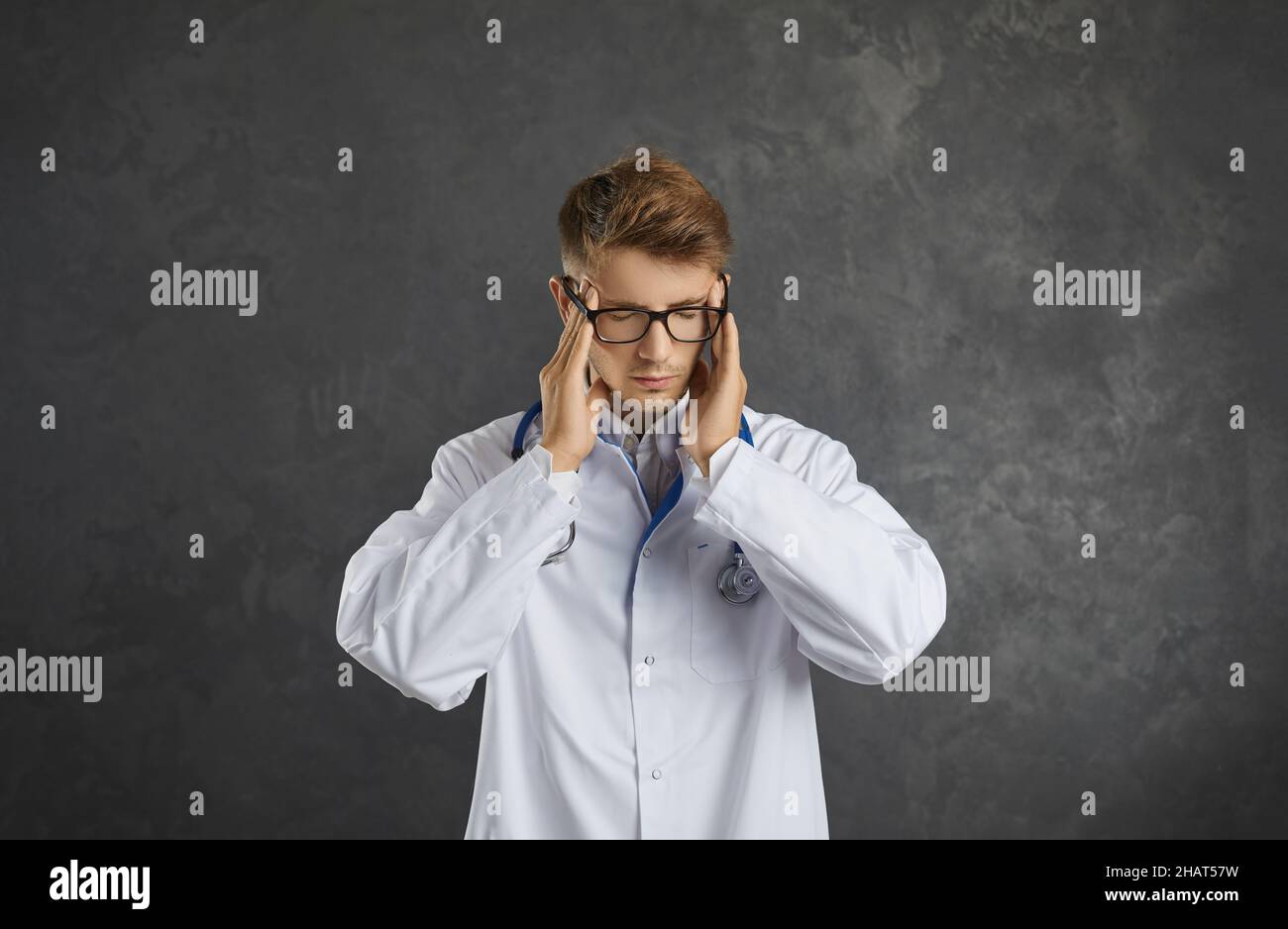 Porträt eines erschöpften jungen männlichen Arztes mit starken Kopfschmerzen und Unwohlsein. Stockfoto
