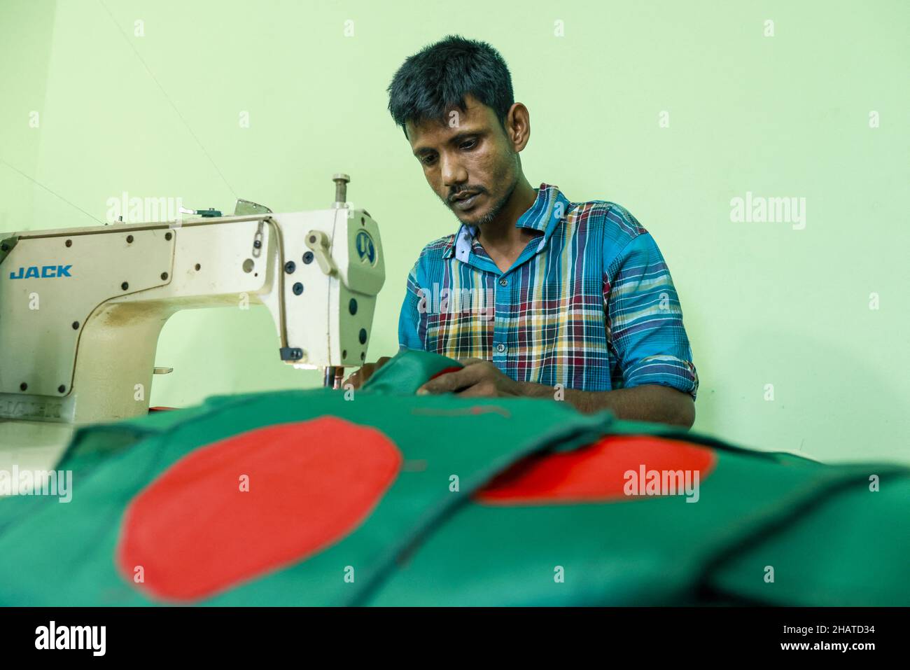 Ein Arbeiter näht die Nationalflagge von Bangladesch vor dem Siegesstag in Narayanganj, am Stadtrand von Dhaka, Bangladesch, am 14. Dezember 2021. Am 16. Dezember wurde zum Gedenken an den Sieg der Streitkräfte Bangladeschs über die pakistanischen Streitkräfte im Befreiungskrieg von Bangladesch im Jahr 1971 ein Siegestag gefeiert. Der Kommandeur der pakistanischen Streitkräfte, General AAK Niazi, gab sich mit seinen Truppen den alliierten Kräften von Bangladesch hin, was das Ende des 9 Monate andauernden Bangladesh Liberation war und 1971 den Völkermord in Bangladesch und die offizielle Abspaltung Ostpakistans nach Bangladesch bedeutete. Foto von S Stockfoto