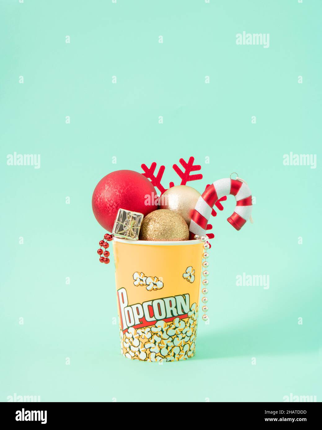 Weihnachten kreatives Konzept der roten Neujahrsdekoration in Popcornbox. Winterjause für das Kino auf pastellfarbenem minzfarbenem Hintergrund. Stockfoto