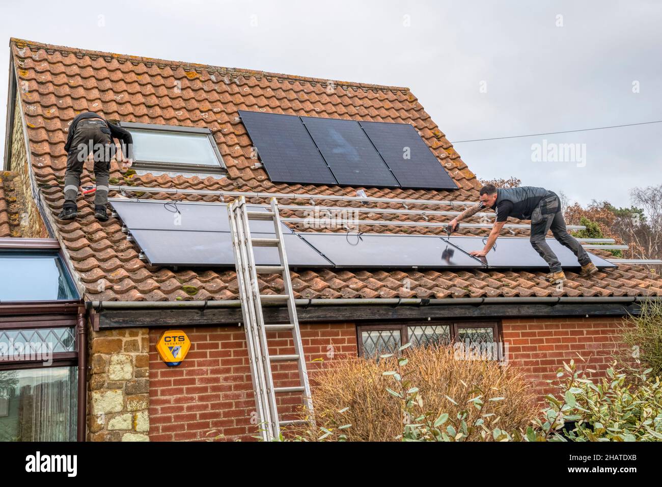 Arbeiter installieren Solarzellen oder pv-Zellen auf dem Pantiled Dach eines Norfolk-Häuschens. NB: Die Räumlichkeiten auf dem Foto sind Eigentum freigegeben. Stockfoto