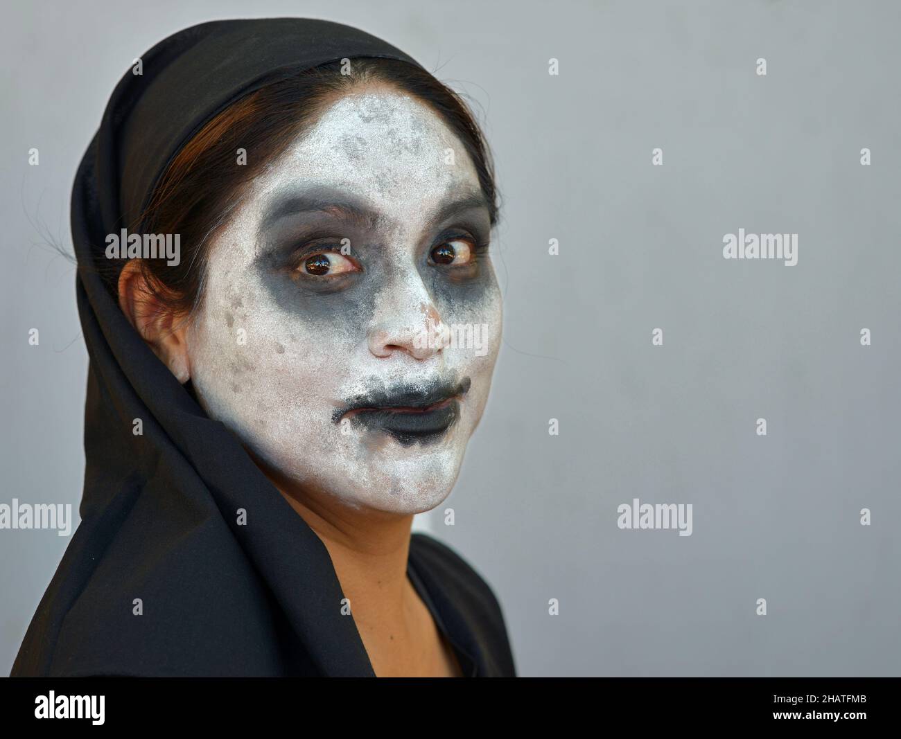 Die junge Mexikanerin mit einem traditionellen weißen Zombie-ähnlichen Catrina-Gesicht-Make-up am Tag der Toten (Día de los Muertos) trägt schwarze Kleidung. Stockfoto