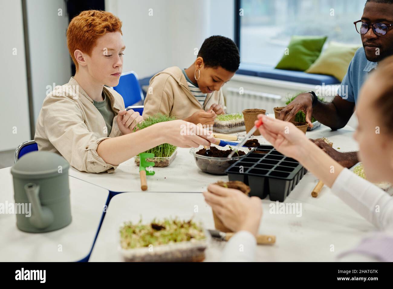 Verschiedene Gruppe von Kindern, die Samen Pflanzen, während sie während des Biologieunterschurs in der Schule experimentieren Stockfoto