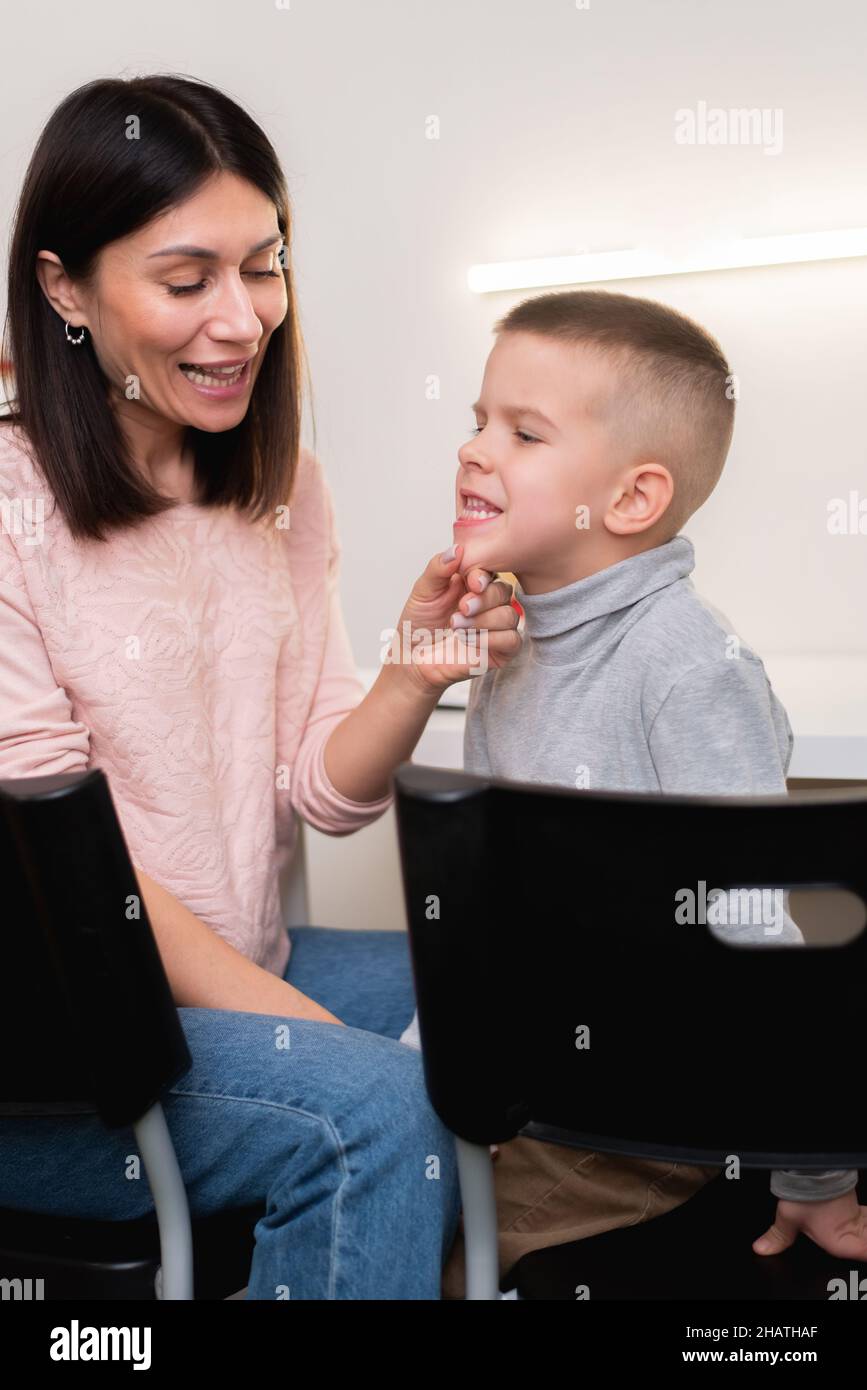 Eine schöne Frau Logopädin beschäftigt sich mit dem Jungen und lehrt ihn die richtige Aussprache und kompetente Rede. Stockfoto