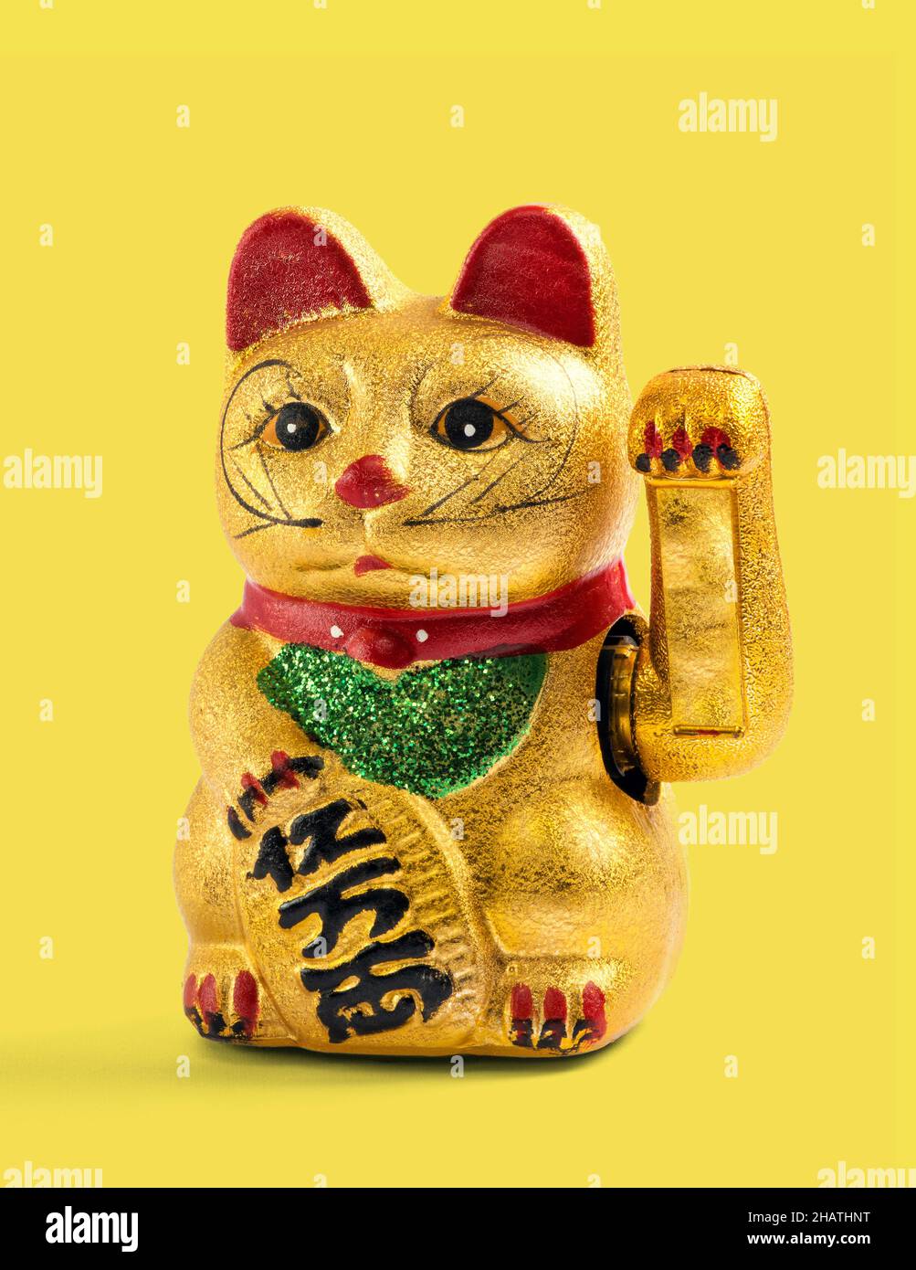 Vergoldete chinesische, asiatische oder Feng Shui Glücksbringer-Katze mit einer Pfote, die als Gruß auf einem gelben Hintergrund Reichtum und Wohlstand anprangt Stockfoto