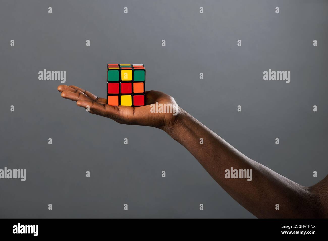Crop unkenntlich afroamerikanischen Person Demonstration bunten Rubik 's Würfel vor grauem Hintergrund im Studio Stockfoto
