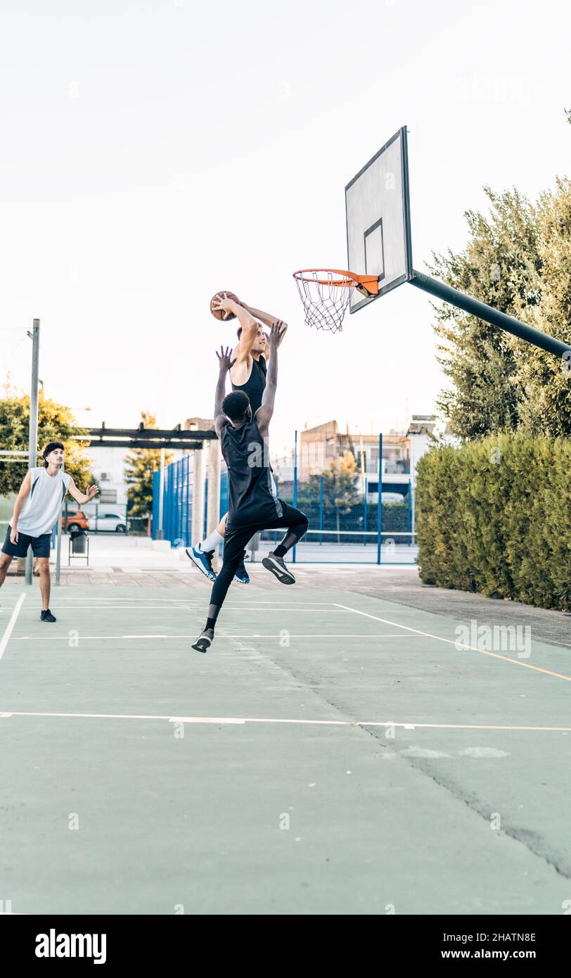 Vertikales Foto eines Mannes, der während eines freundlichen Basketballspiels springt, um Punkte zu erzielen Stockfoto