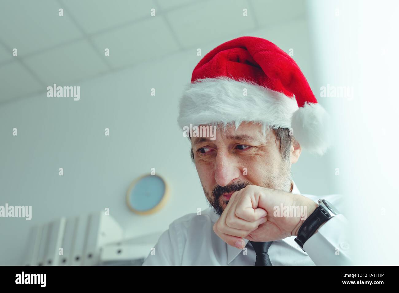 Bedauert Geschäftsmann mit Weihnachtsmann Hut leiden an Weihnachten Weihnachtszeit Depression im Büro, selektive Konzentration Stockfoto