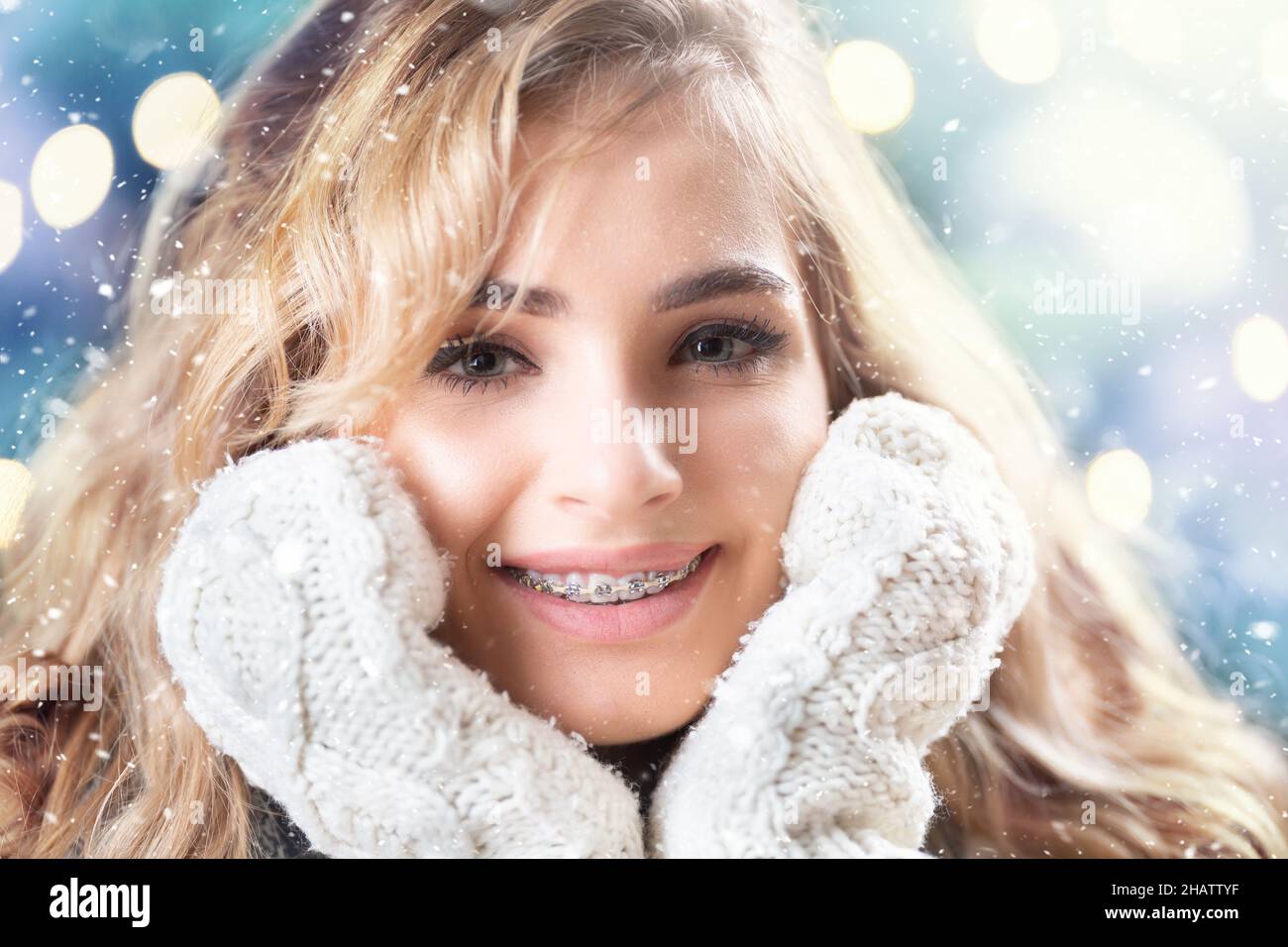 Schöne lächelnde Blondine mit Zahnspange im Winter Schneefall. Stockfoto