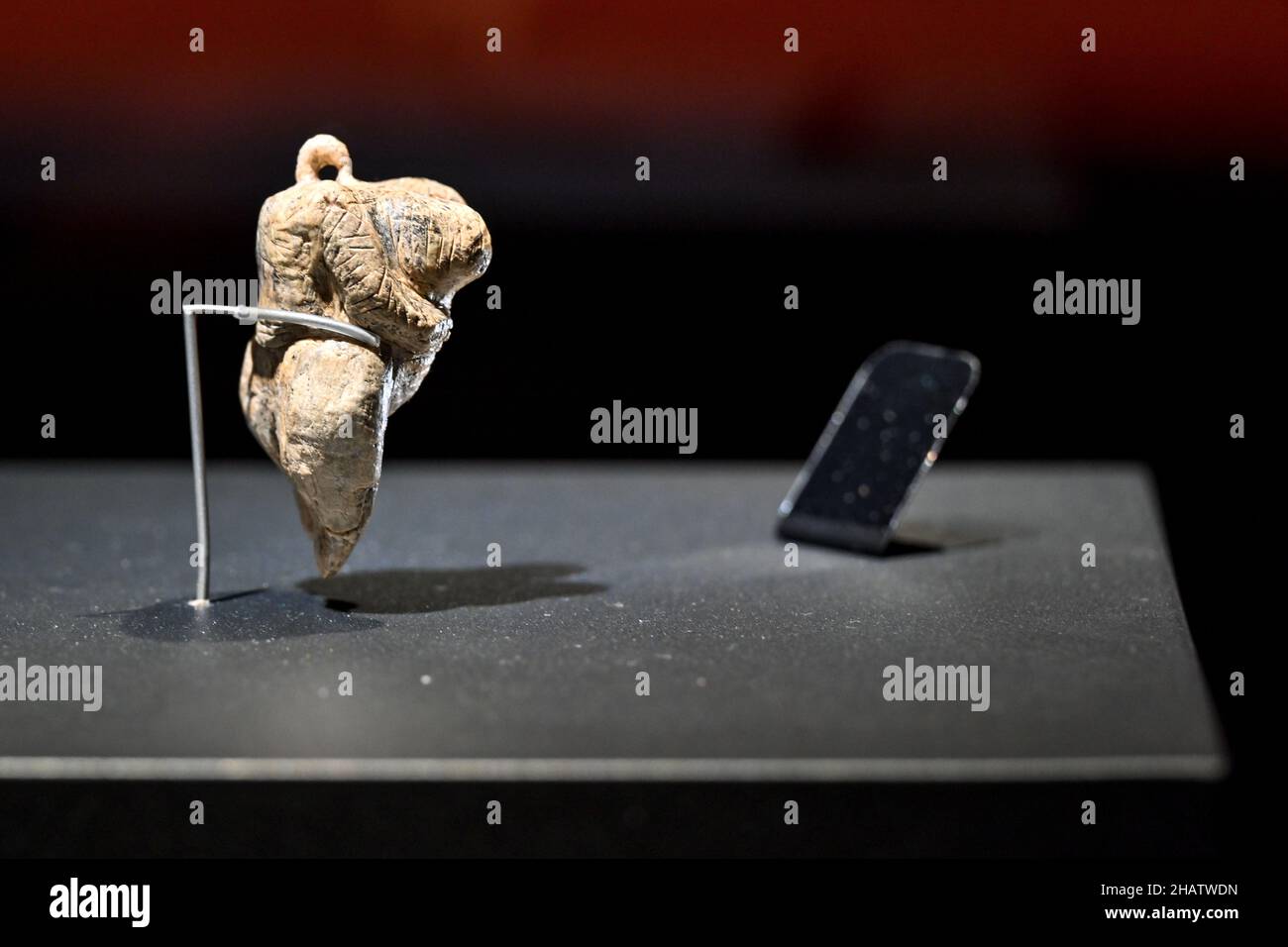 15. Dezember 2021, Baden-Württemberg, Blaubeuren: Die älteste figurative Darstellung eines Menschen der Welt steht in einer beleuchteten Vitrine. Die sogenannte Venus der Hohen Fels ist etwa sechs Zentimeter hoch, aus Mammutelfenbein gefertigt und rund 40.000 Jahre alt. Die geschnitzte Venusfigur wurde im September 2008 bei Ausgrabungen in der Hohle Fels Karsthöhle am südlichen Fuße der Schwäbischen Alb bei Schelklingen entdeckt. Die Venusfigur stammt aus der oberpaläolithischen Kultur des Aurignacian. Das Prähistorische Museum (urmu) im UNESCO-Weltkulturerbe wird sein Stockfoto