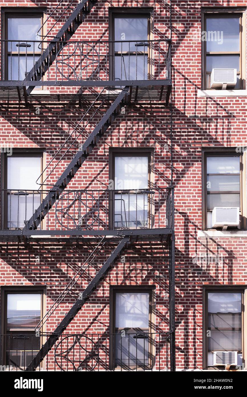 Bronx-Gebäude aus rotem Backstein mit schwarzer Feuerschutzanlage aus Metall und Schattenhintergrund Stockfoto