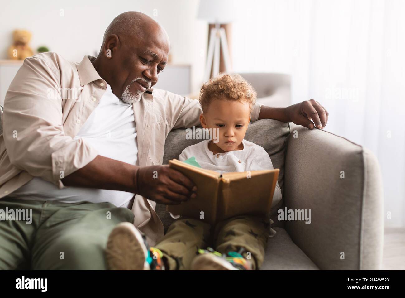 Afroamerikanischer Großvater Und Kleiner Enkel Lesebuch Zu Hause Stockfoto