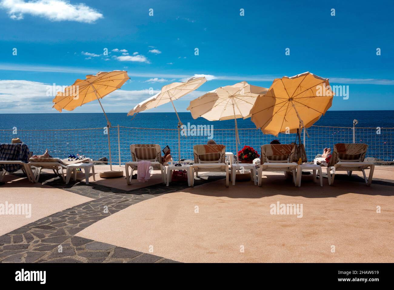 Liegestühle und Sonnenschirme am Pool mit Blick auf den Atlantik in Funchal, Madeira, Portugal Stockfoto