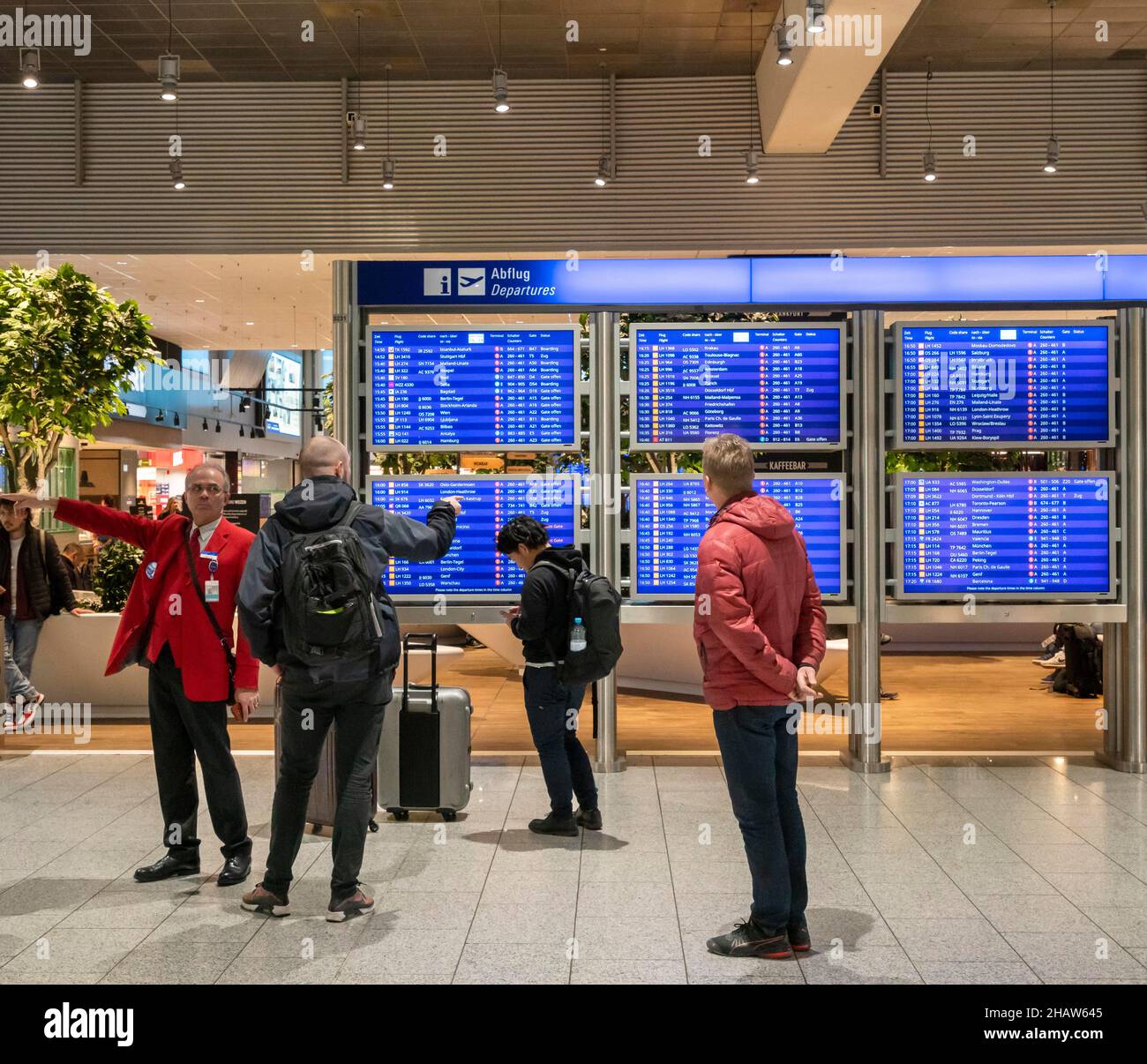 Passagiere und Mitarbeiter stehen vor den blauen Bildschirmen für die Abflugzeiten am Frankfurter Flughafen, Frankfurt, Hessen, Deutschland Stockfoto
