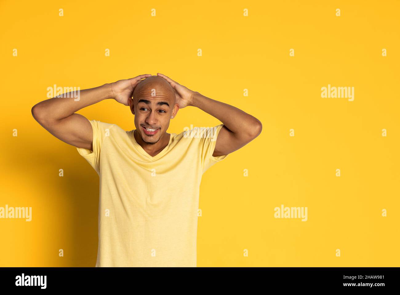 Emotionaler dunkelhäutiger Mann im T-Shirt, der isoliert auf gelbem Studiohintergrund posiert. Konzept der menschlichen Emotionen Stockfoto