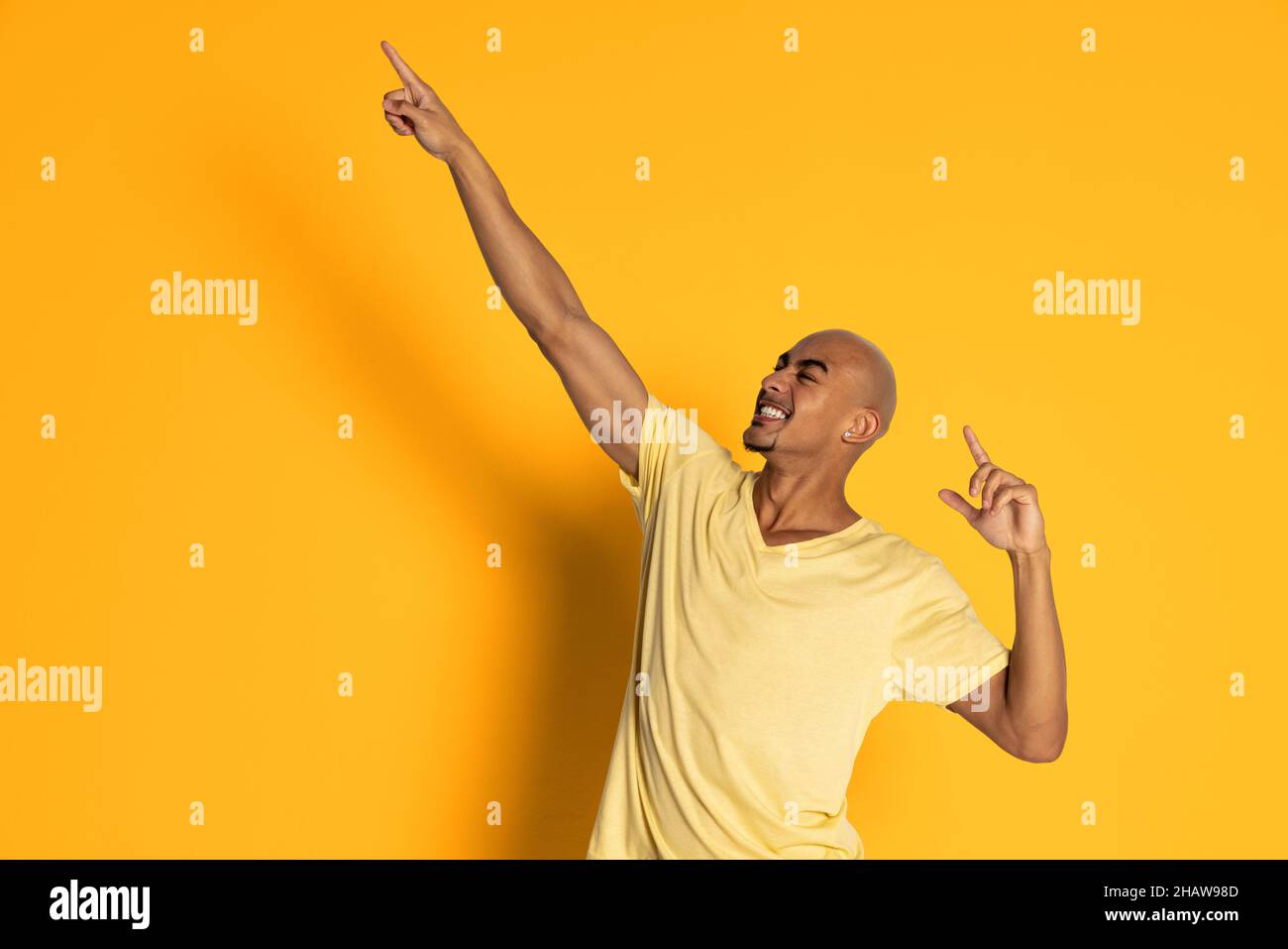 Aufgeregt dunkelhäutiger Mann in T-Shirt posiert isoliert auf gelbem Studiohintergrund. Konzept der menschlichen Emotionen Stockfoto