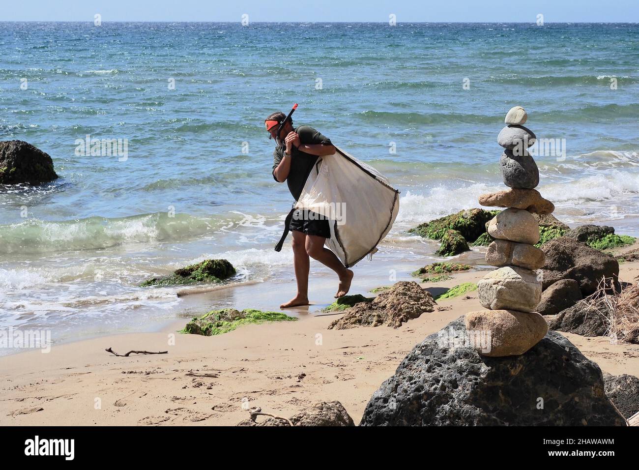 Mann in Taucherbrille schleppt schweren Beutel mit Plastikmüll, Strandreinigung, Almeria, Andalusien, Spanien Stockfoto