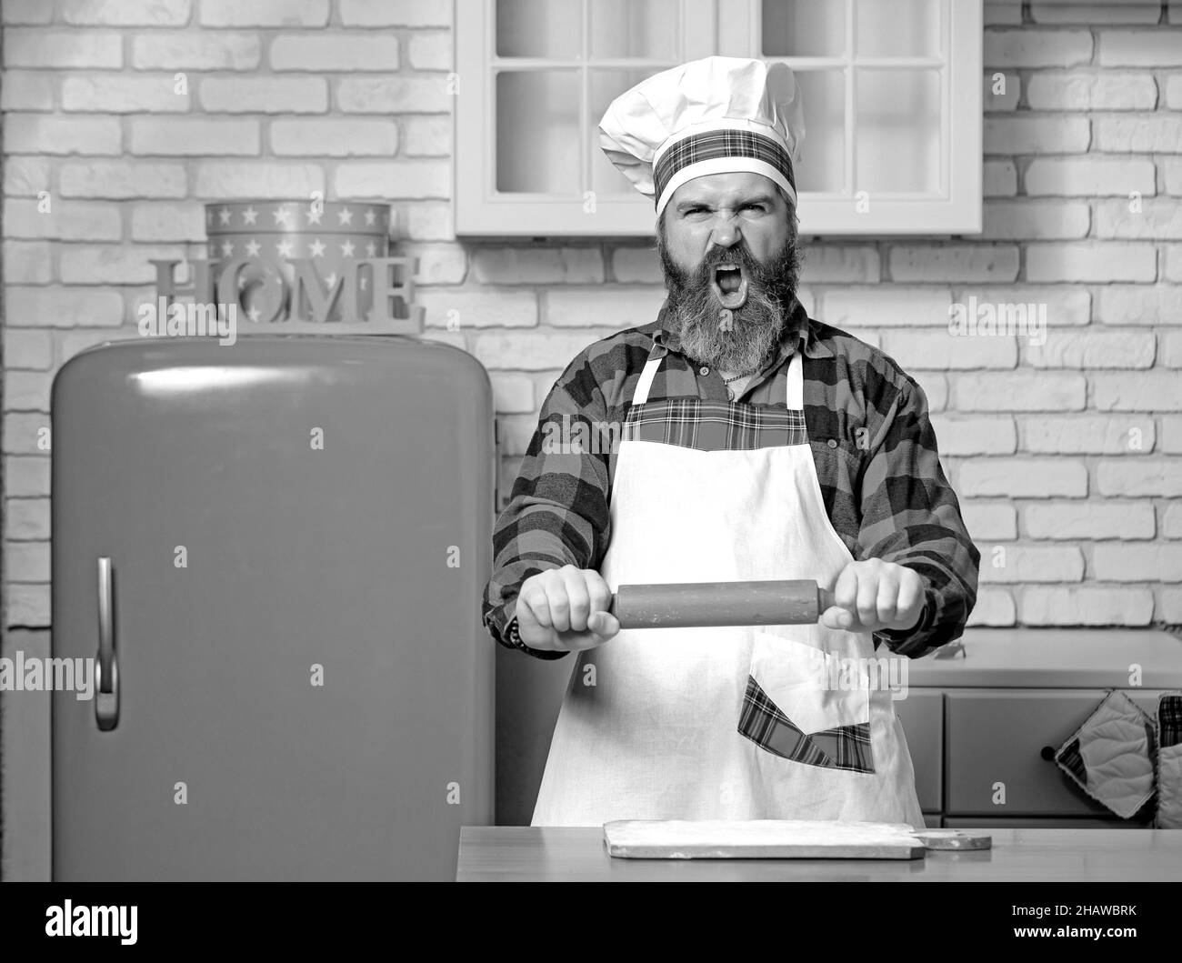 Wütend Koch Bäcker Mann Anheben von Nudelholz bedrohlich in der weißen Küche. Stockfoto