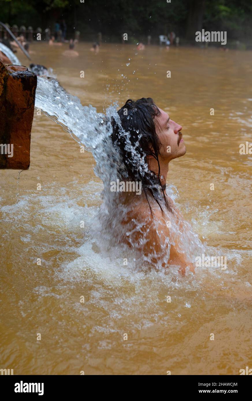 Botanischer Garten, Mann unter Wasserstrahl im Thermalwasserpool im Terra Nostra Park, Furnas, Sao Miguel Island, Azoren, Portugal Stockfoto