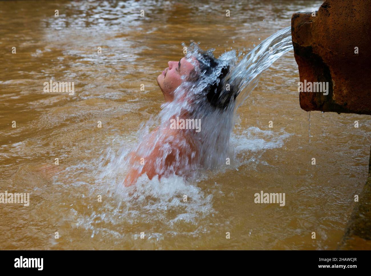 Botanischer Garten, Mann unter Wasserstrahl im Thermalwasserpool im Terra Nostra Park, Furnas, Sao Miguel Island, Azoren, Portugal Stockfoto