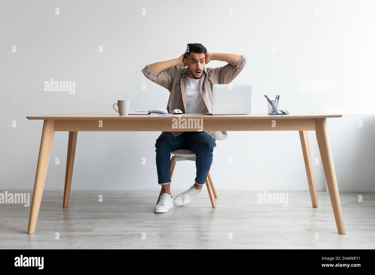 Schockiert arabischen Kerl greifen Kopf mit Laptop Stockfoto