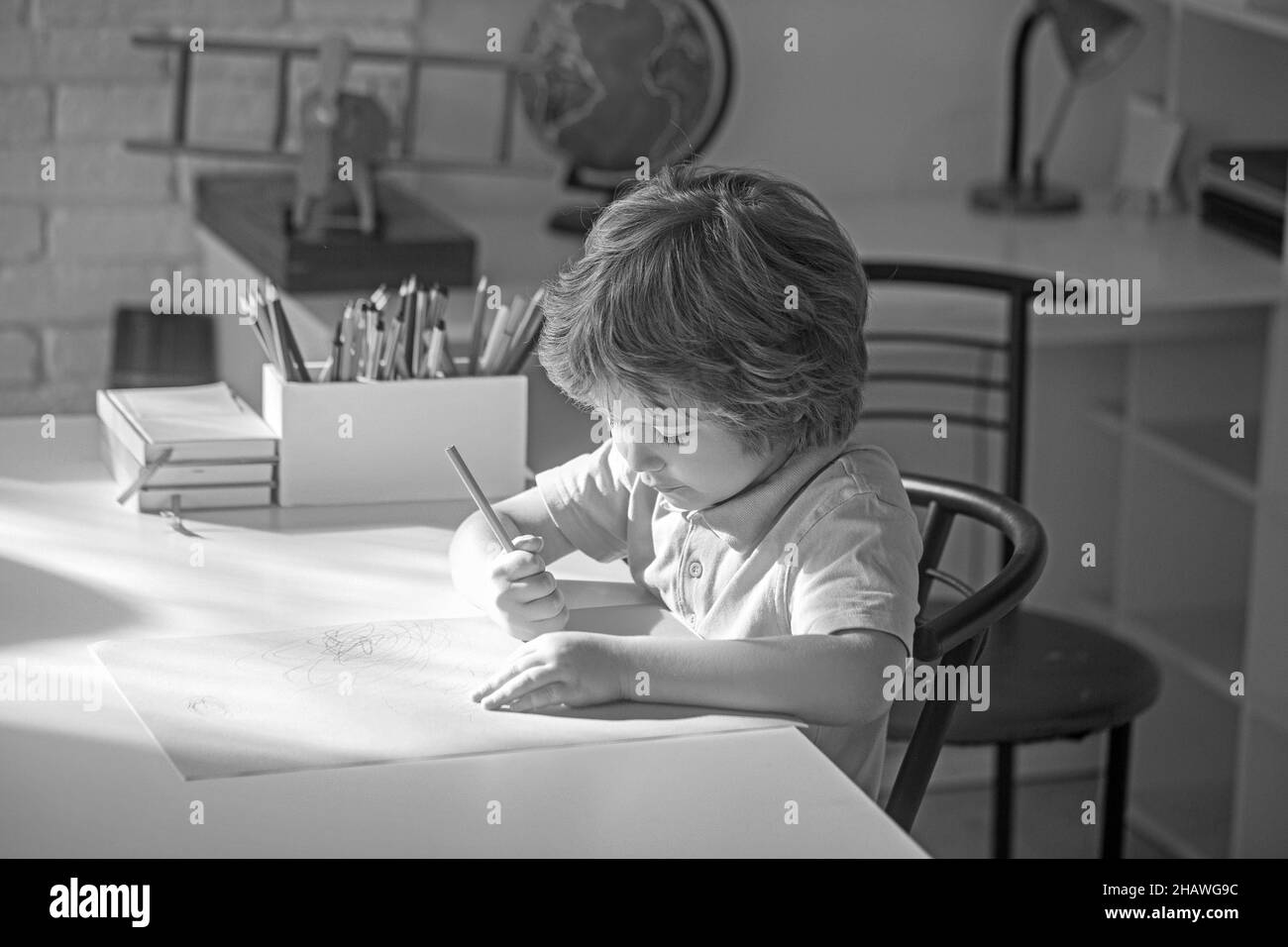 Junge männliche Schüler Zeichnung mit Bleistift im Klassenzimmer. Stockfoto