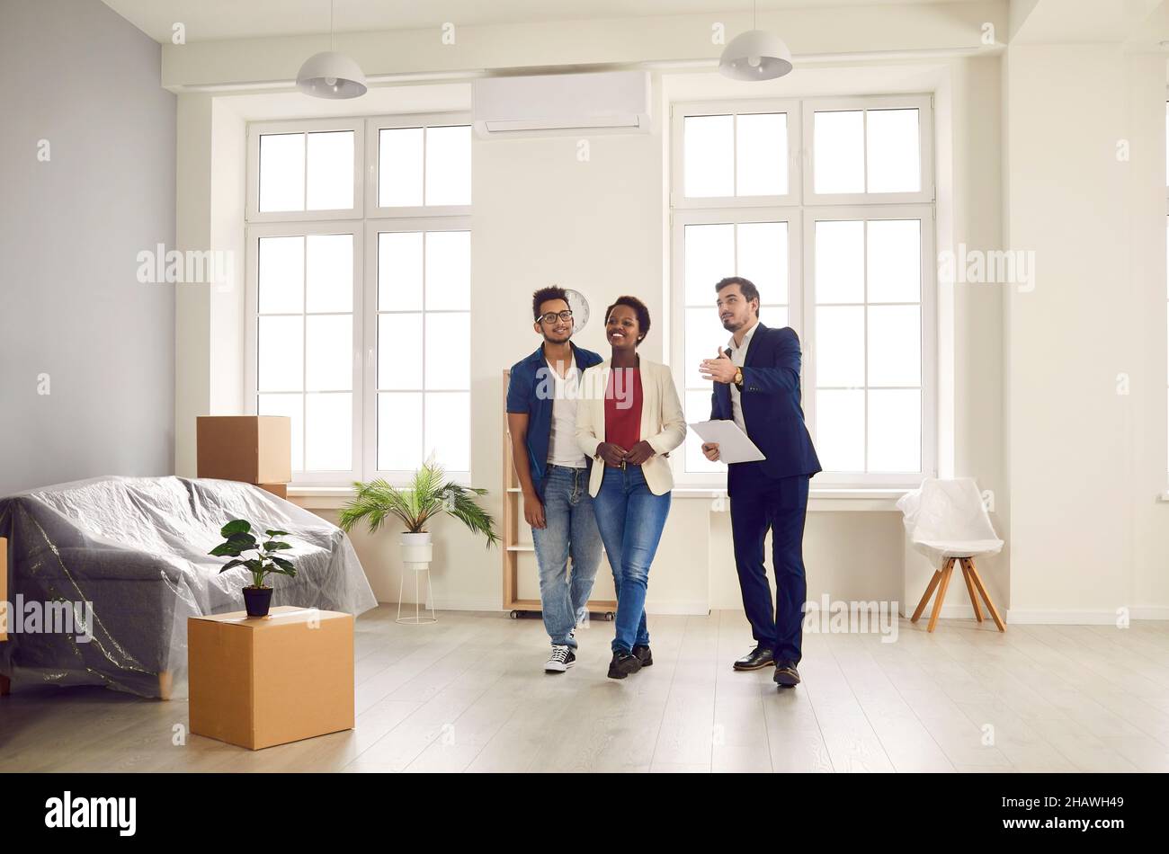 Männliche Immobilienmakler zeigt Wohnung zum Verkauf an junge afroamerikanische Familie. Stockfoto