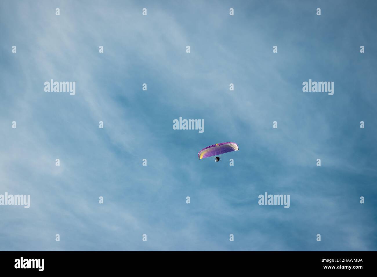 Nicht erkennbarer Fallschirmspringer Paragliding mit Fallschirm am blauen Himmel mit kleinen Wolken. Adenaline und extreme sportliche Aktivitäten im Freien Stockfoto