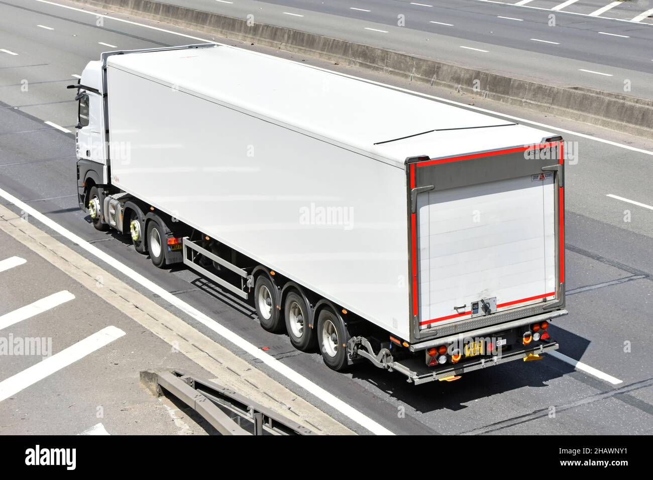 Weiß unmarkiert sauberer lkw-Lieferkettentransport LKW-Sattelanhänger in Luftaufnahme und Rückansicht auf englischer britischer Autobahnstraße Stockfoto