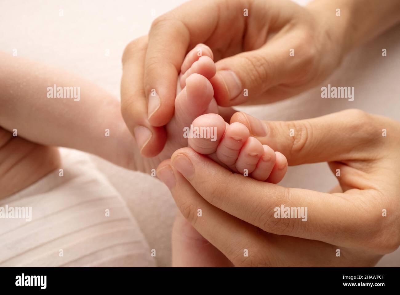 Die Handflächen des Vaters, die Mutter, halten den Fuß des Babys. Stockfoto