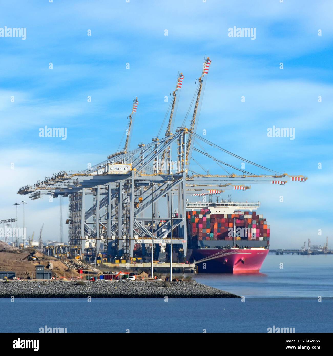 Großes Containerschiff und volle Ladung von Transportcontainern unter riesigen hohen Kranen, die am Mündungshafen London Gateway Thames andockten, um Essex UK zu entladen Stockfoto