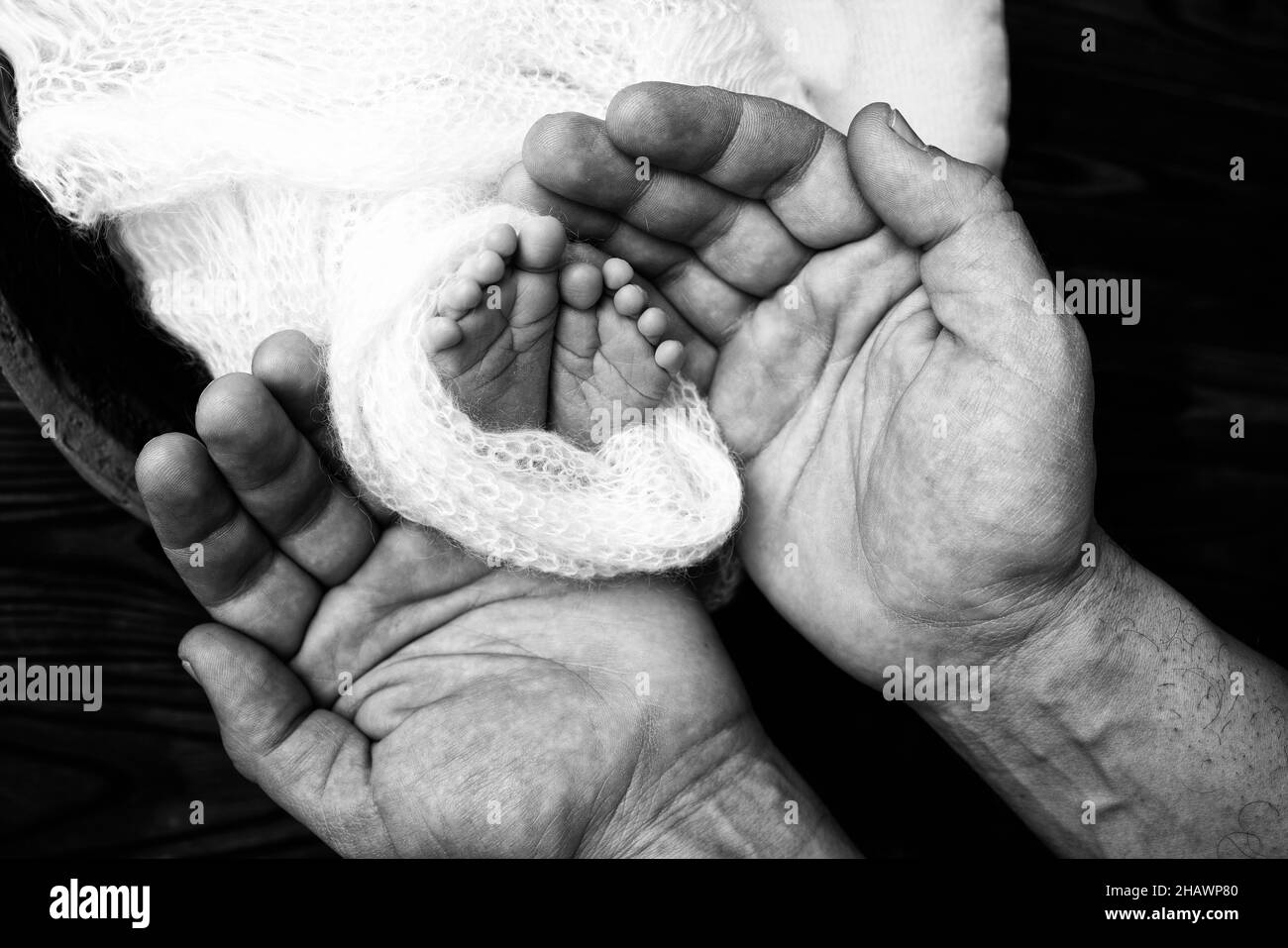 Die Handflächen des Vaters, die Mutter, halten den Fuß des Babys. Stockfoto