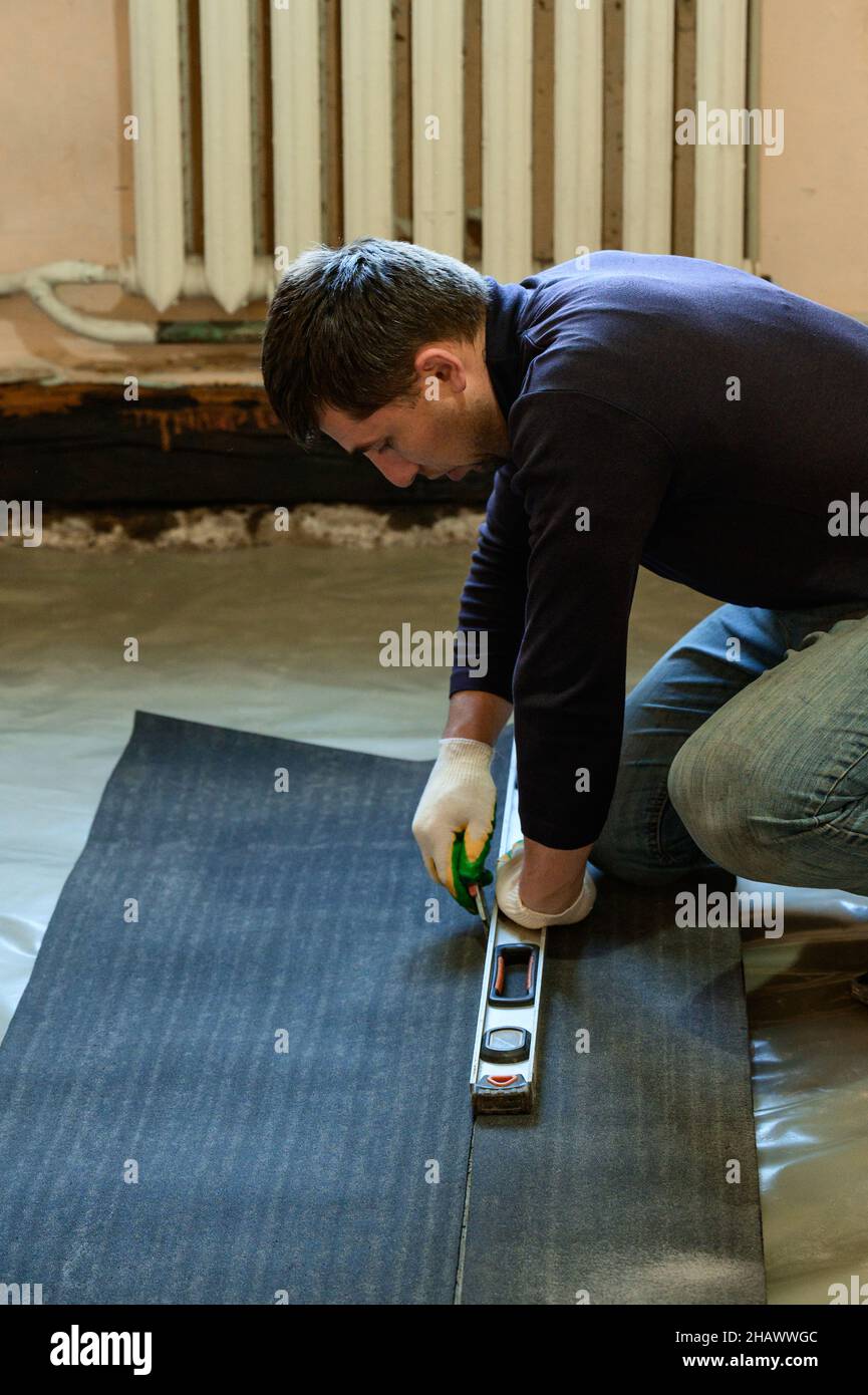 Die Bänder des Dachmaterials, schneidet der Meister die Dachmaterialien aus der Rolle, der Abdichtung des Bodenbelags, den Reparaturarbeiten. Stockfoto