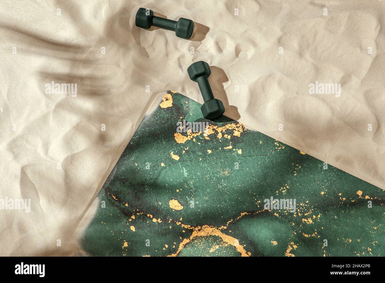 Nicht gerollte grüne Moos-Yogamatte und Kurzhanteln am Sandstrand. Entspannung und Meditation Wohlbefinden. Achtsames Lebenskonzept Stockfoto