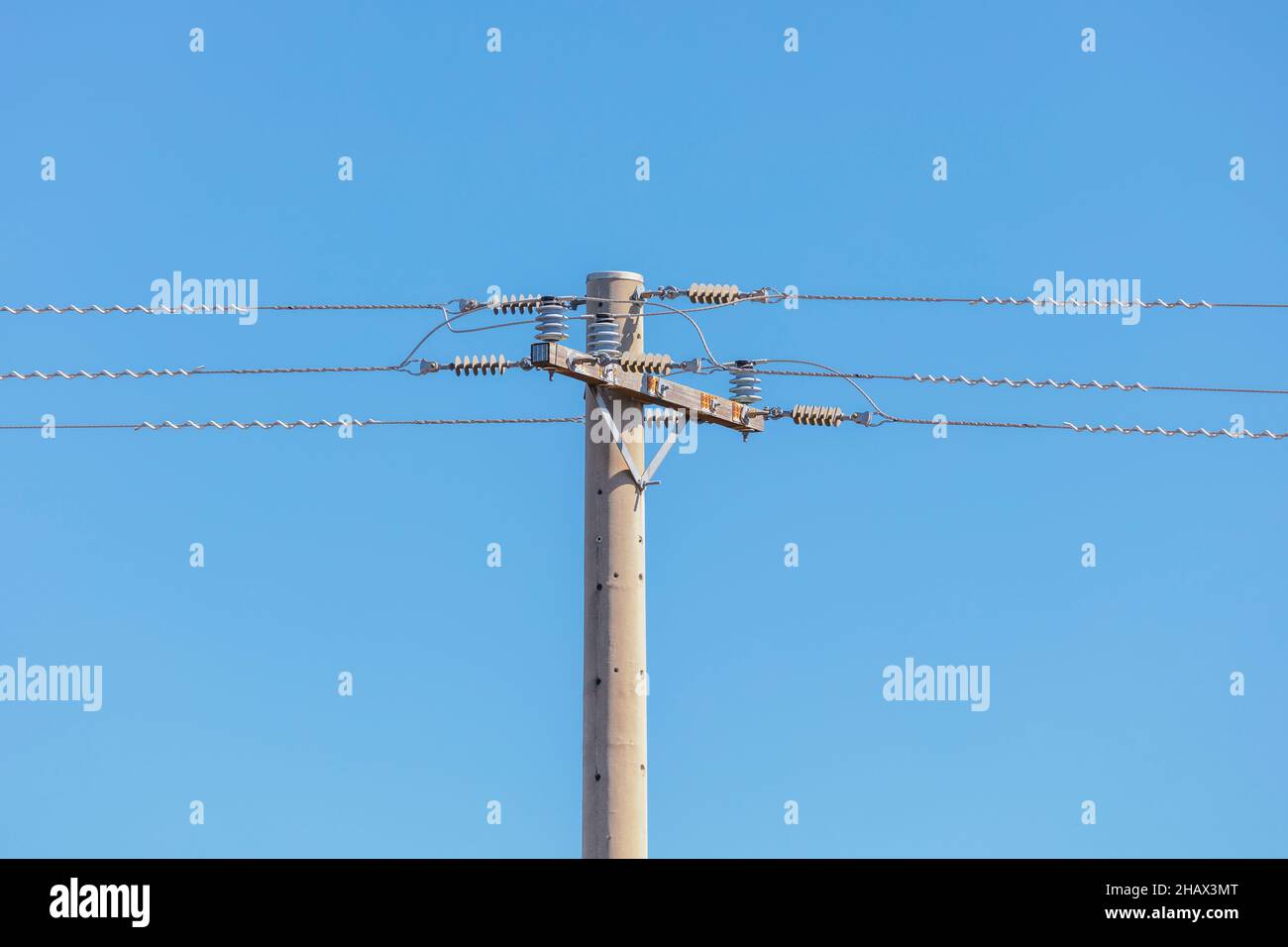 Foto eines Telefonpfostens aus Beton und Kabel vor blauem Himmel Stockfoto