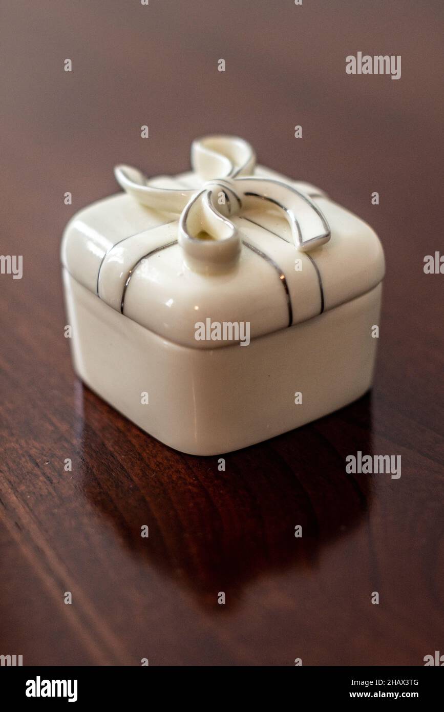 Weiße Keramik Geschenk-Box geformten Ring-Box mit Band und Schleife auf Holztisch Stockfoto