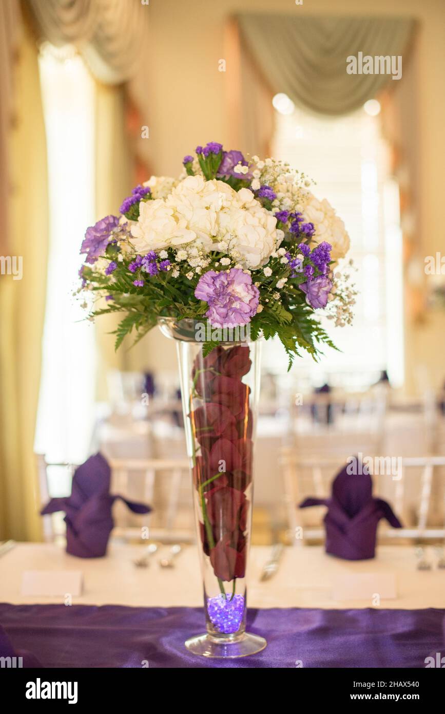 Hohe lila und weiße Blumen im Mittelpunkt bei der Hochzeitsfeier Stockfoto