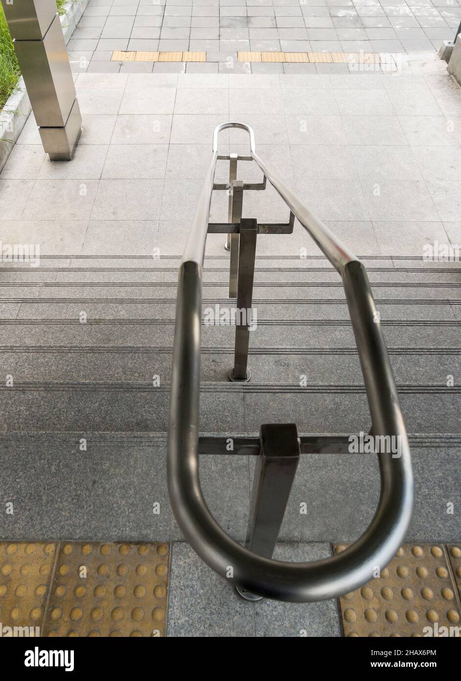 Der Handlauf aus Edelstahl auf der Treppe in der Nähe des Eingangs zum städtischen Bahnhof, Vorderansicht mit dem Kopierraum. Stockfoto