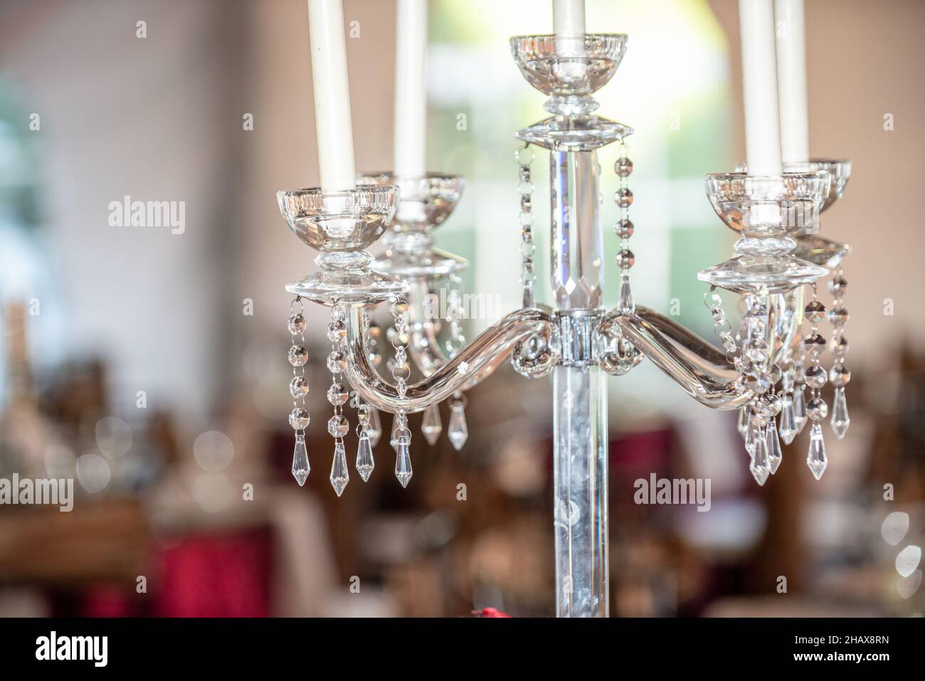 Kunstvoller Kerzenhalter aus Kristall mit weißen Kerzen im Empfangsbereich Stockfoto