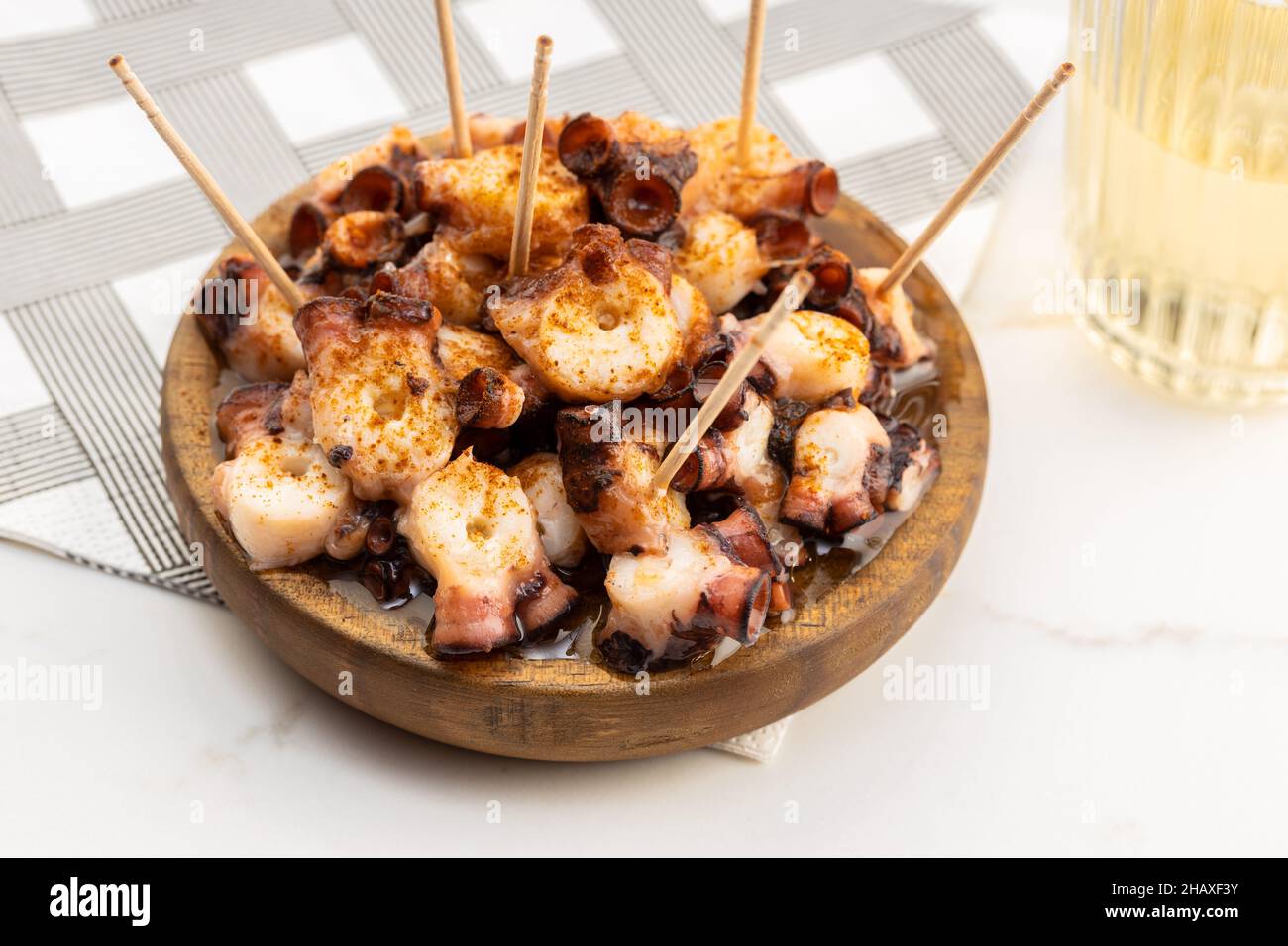 Tintenfisch im galizischen Stil in Holzplatte auf Marmortisch. Typische Vorspeise aus Galicien, Spanien. Pulpo a Feira Stockfoto