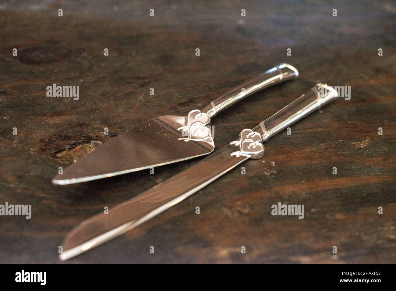 Silberne Kuchengeschirr mit Herzmotiven auf Holztisch Stockfoto